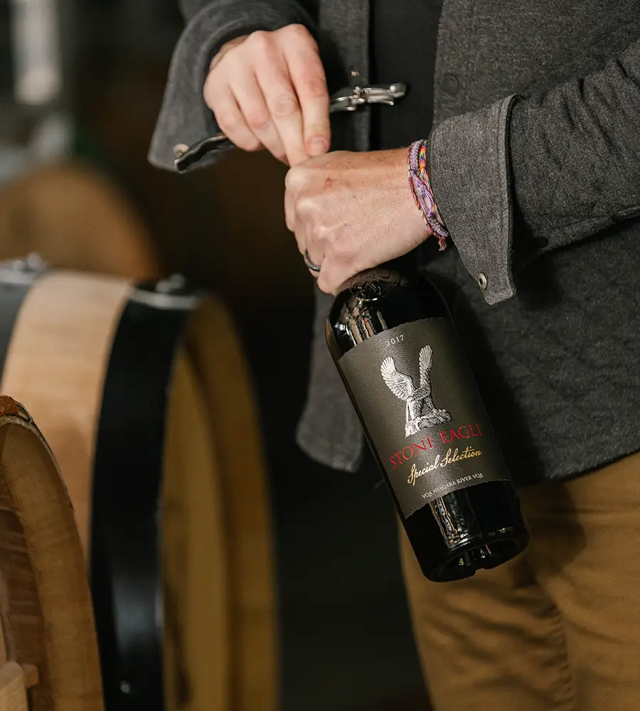 Person opening a bottle of Stone Eagle Wines.